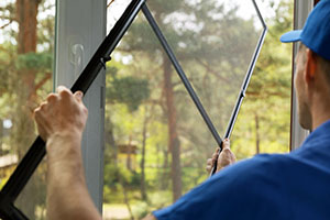 man installing mosquito net wire mesh on house window